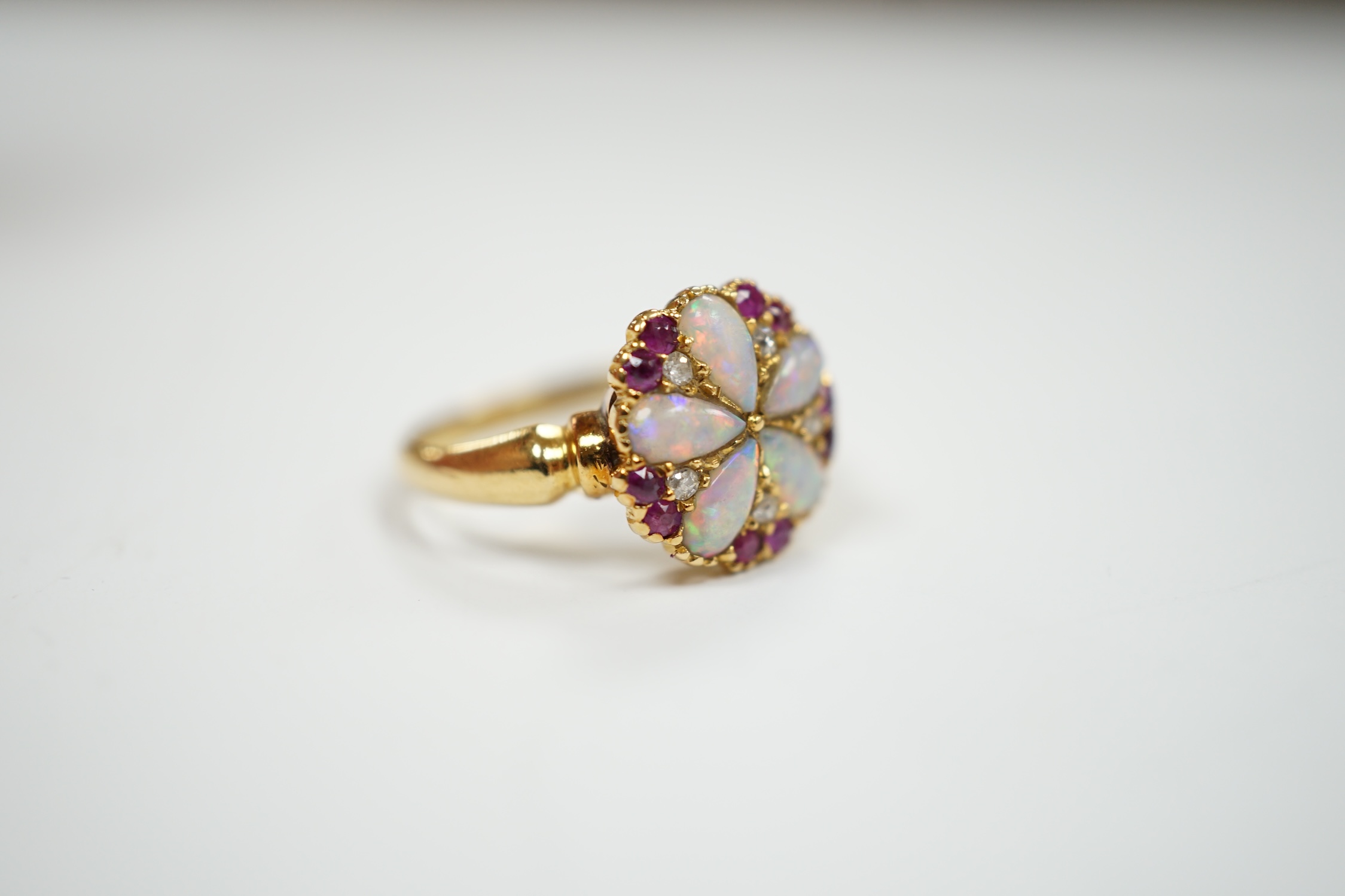 An Edwardian 18ct gold, white opal, ruby and diamond cluster set ring, size K, gross weight 3.1 grams.